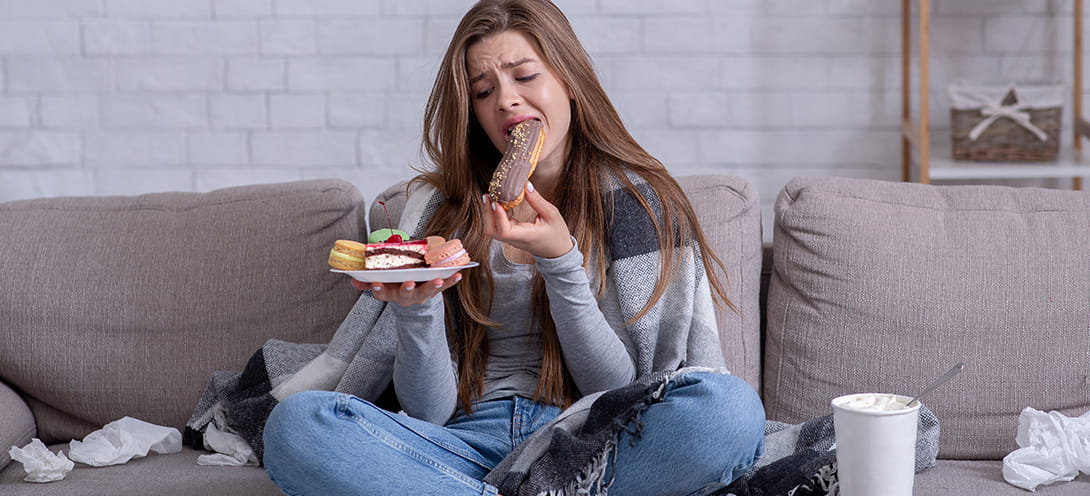 Kobieta zajadająca stres wysokoprzetworzoną żywnością