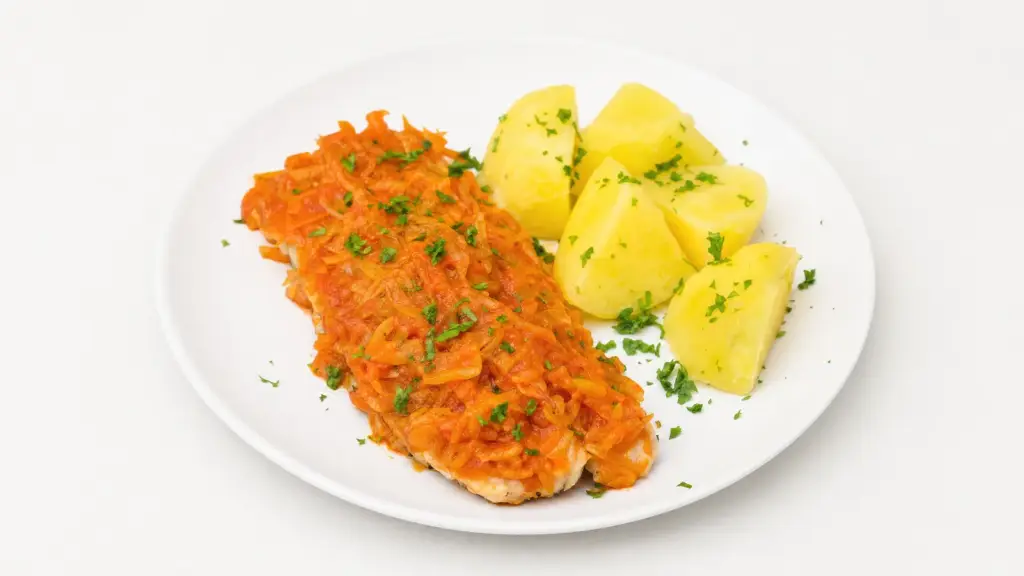 Ryba po grecku z pieczonym dorszem pod warzywami duszonymi w koncentracie pomidorowym, z gotowanymi ziemniakami na białym talerzu